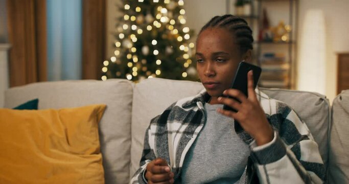 Winter evening. Attractive girl of African appearance sitting on couch. The phone rang and she picked up the phone. She learned about the terrible event, talks emotionally and gestures with hands.