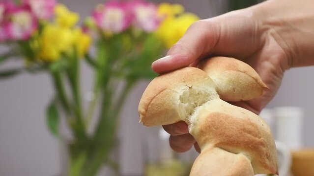 Female hand breaking freshly baked epi baguette.
