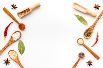 Cooking background with colorful spices and herbs in wooden spoons, top view