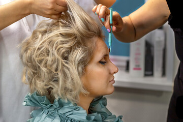 Fototapeta premium Applying makeup in a beauty salon. close-up. The master's hand holds a brush and paints a woman's eyebrows with dark paint.