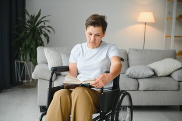 Shot of a senior woman sitting in a wheelchair and reading book at home