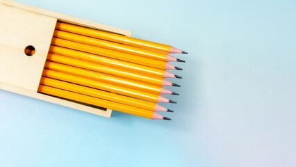 Set of simple graphite pencils in a wooden pencil case. New pencils in a wooden box. Banner, space for text. Back to School concept, top view.