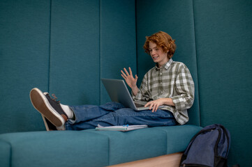 Ginger boy sitting with a laptop and having a video call
