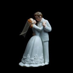 A wedding cake topper on top of the newlyweds dessert.