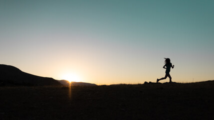 Obraz na płótnie Canvas girl runs at sunset in the mountains.