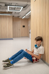 A boy sitting on the floor and doing his homework