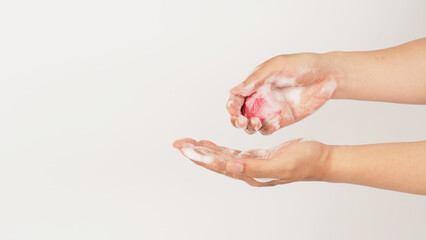 Hands washing with foaming and pink soap on white background. Studio shot