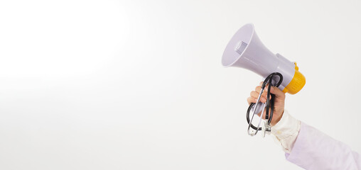 Fototapeta premium Megaphone and stethoscope in doctor's hand on white background. Studio shooting.