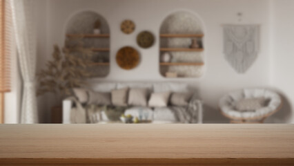 Empty wooden table, desk or shelf with blurred view of bohemian wooden living room in boho style. White sofa with pillows, modern interior design concept