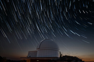 Astronomical observatory under star trails sky at night - obrazy, fototapety, plakaty