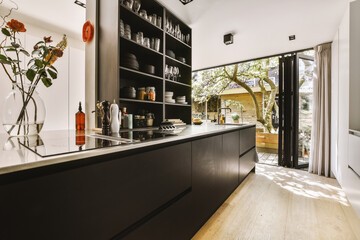 Interior of black kitchen and dining room with balcony doors in contemporary apartment at daytime