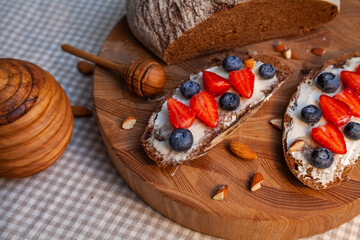 Sandwiches with homemade rye bread, honey, cheese and berries