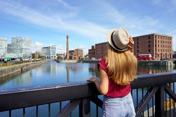 Tourism in Liverpool, UK. Back view of traveler girl on Swing Bridge visiting the Royal Albert Dock...