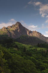 A beautiful sunset behind a mountain range at the base of which is a green dense forest