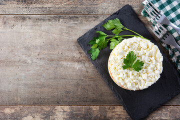 Traditional Russian layered salad Mimosa on wooden table. Copy space