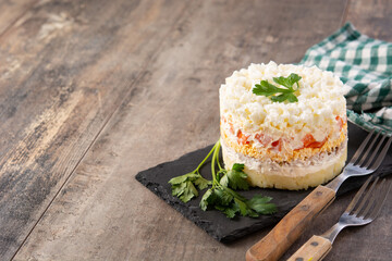 Traditional Russian layered salad Mimosa on wooden table. Copy space