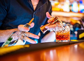 man bartender hand making negroni cocktail. Negroni classic cocktail and gin short drink with sweet vermouth, red bitter liqueur