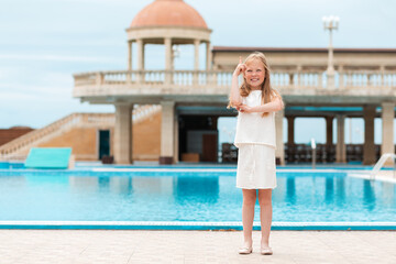 Fototapeta na wymiar Emotions. A cute girl with a smile shows a thumbs up. The pool is in the background