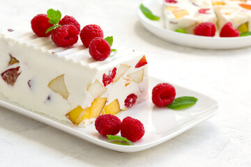fruit dessert. ice cream with pieces of fruit and ripe raspberries on a white dish