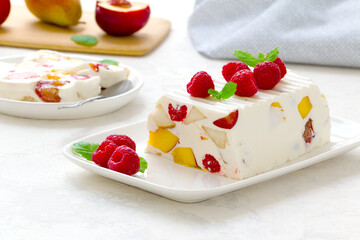 fruit dessert. ice cream with pieces of fruit and ripe raspberries on a white dish