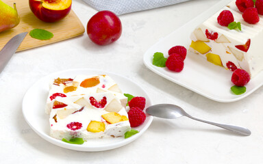fruit dessert. ice cream with pieces of fruit and ripe raspberries on a white dish