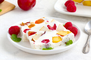 fruit dessert. ice cream with pieces of fruit and ripe raspberries on a white dish