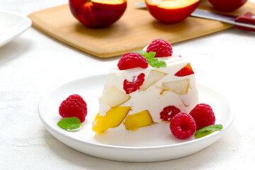 fruit dessert. ice cream with pieces of fruit and ripe raspberries on a white dish