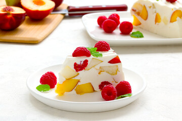 fruit dessert. ice cream with pieces of fruit and ripe raspberries on a white dish