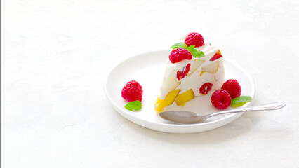fruit dessert. ice cream with pieces of fruit and ripe raspberries on a white dish