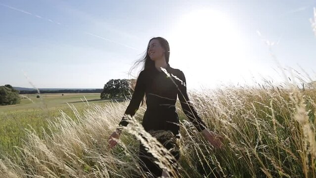 Woman walking in the field enjoying sunset. Slow motion