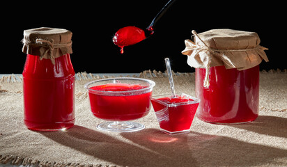 Glass jars and spoon with delicious strawberry, cherry or raspberry jam