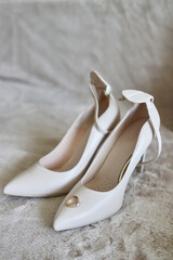 White wedding shoes with a ring on a fabric background.