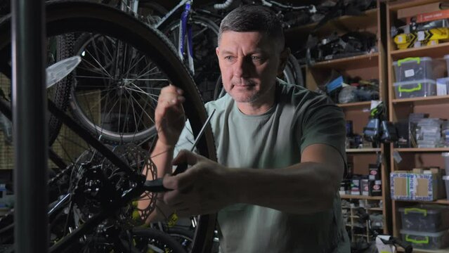 Service engineer performs diagnostics and repairs of bicycle in professional workshop