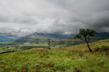 Green slopes in the foothills of the Drakensburg mountains with a cloudy sky