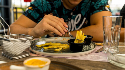 Obraz premium A man is eating fries with ketchup in a restaurant during the day