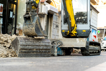 A bulldozer on the street digging a hole