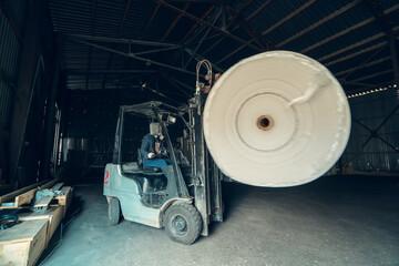 Fototapeta na wymiar Forklift transports large roll of paper at recycling and toilet paper manufacturing plant.