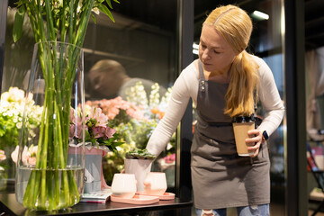 flower shop employee in work process next to a refrigerator with flowers
