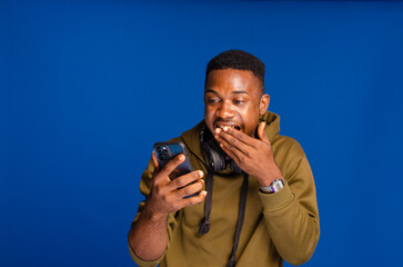 Smiling dark skinned millennial sportsman in headphones choosing music on mobile phone