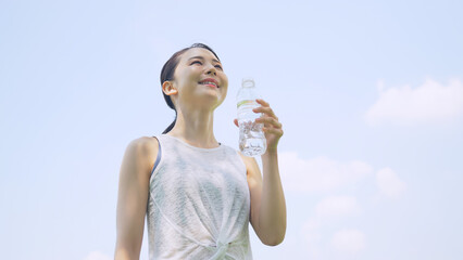 屋外で水を飲む女性　水分補給　熱中症対策
