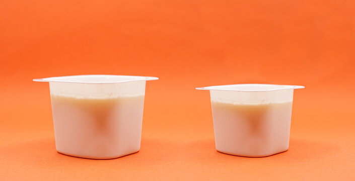 reduced yogurt on an orange background. Inflation, skimpflation or shrinkflation concept of less for the same price.