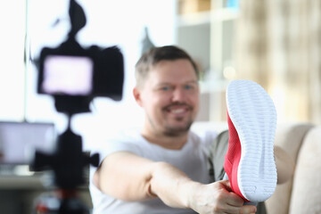 Cheerful male blogger calls red sneakers while recording new video for blog