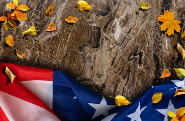 USA flag buried in yellow dry leaves. Autumn texture