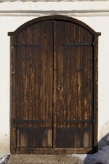 Old wooden door on white painted stone building.