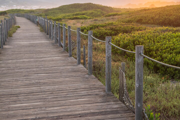 Fototapeta na wymiar selective focus wooden path to the beach on the dunes at sunrise, northern Portugal