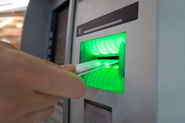 Close-up of a woman's hand taking out a card from an ATM in a shopping center. Selective focus