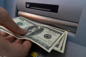 Close-up of a woman's hand withdrawing money from an ATM. Selective focus