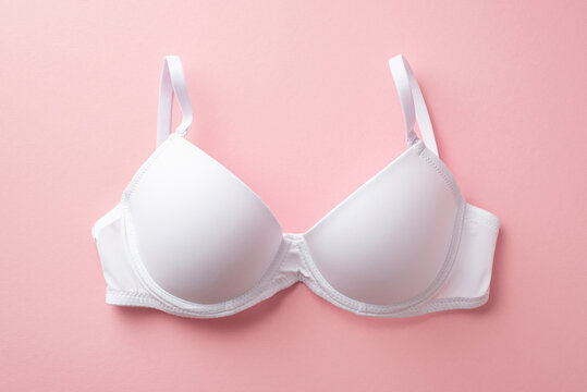 Breast cancer awareness concept. Top view photo of white brassiere on isolated pastel pink background
