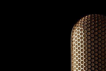Part of the mesh of a gold plated ribbon microphone on a black background Nr.1