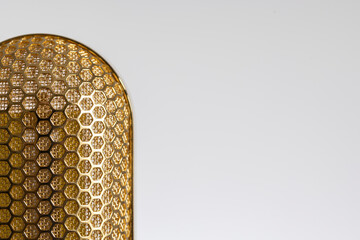 Part of the mesh of a gold plated ribbon microphone on a white background